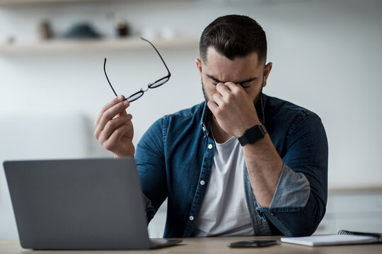 Tired Young Male Feel Pain Eye Strain Hold Glasses, Rubbing Dry Irritated Eyes