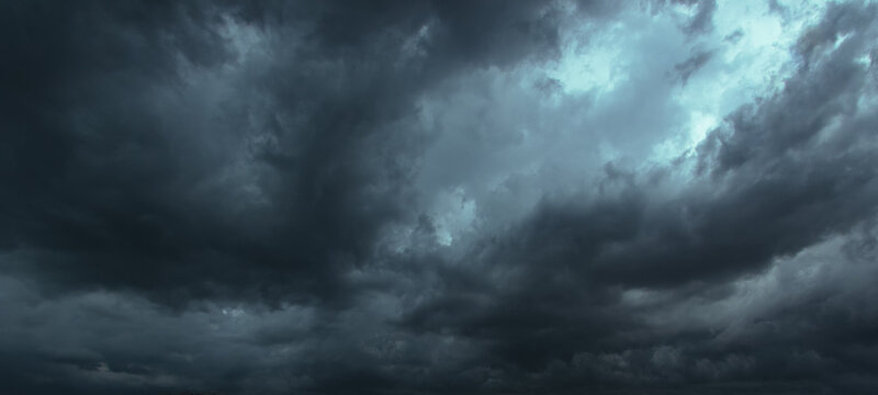 The dark sky had clouds gathered to the left and a strong storm before it rained.Bad or moody weather sky.