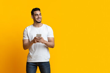 Cheerful arab guy with smartphone looking at copy space