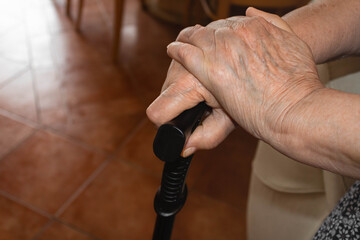A senior woman's hands  holding a walking cane, indoors, top view