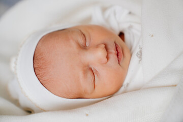 cute Newborn baby sleeps in white clothes. attire for discharge from hospital.