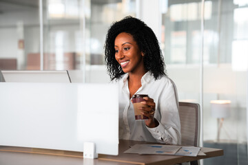 brazilian woman working and drinking coffee in workstation .