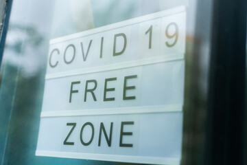 Lightbox with as sign covid 19 free zone behind a glass door of the cafe. We're open again after quarantine, video of small business owner. The business works after vaccination