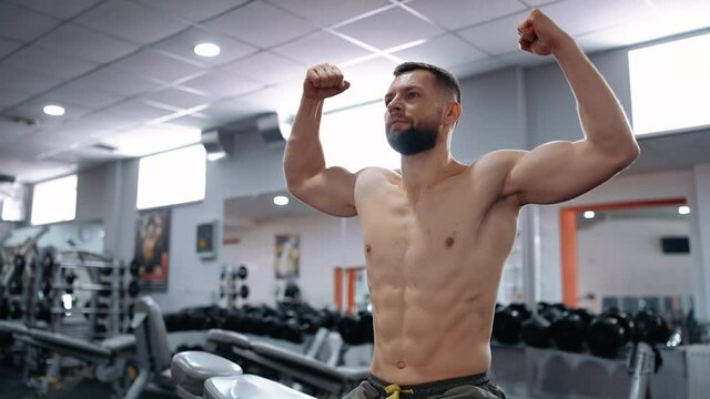 The bodybuilder tenses his muscles, looks straight ahead, without a shirt. Intense masculine energy. Healthy lifestyle. Sport concept