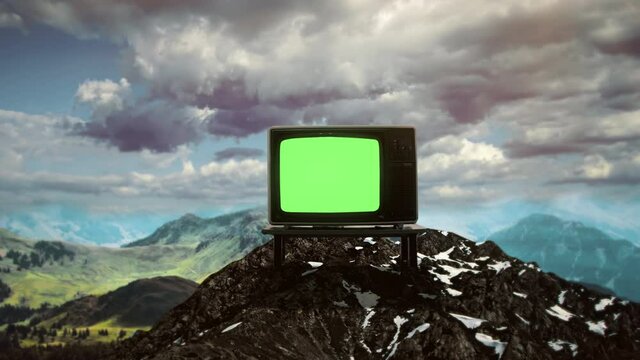 Mountain Top Green Screen TV Zoom In Vintage Television. Vintage green screen television on top of a mountain under a cloudy sky. Zoom in