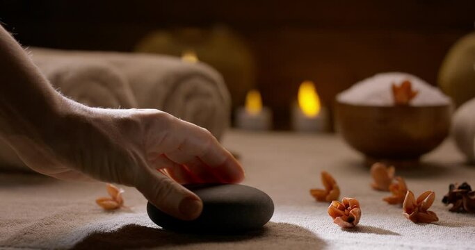 Spa salon equipment. Close up shot of hand putting massage hot stones on table. Towels and bath salt prepared for procedures 4k footage