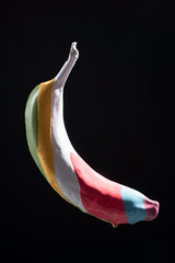 multicolored paint on banana stripes, levitation of multicolored banana on black background