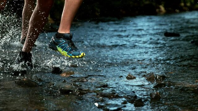 Super slow motion of men feet running in river, splashing around. Filmed on high speed cinema camera, 1000 fps.