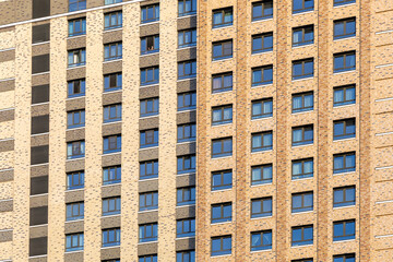 Lots of windows on the facade of a modern residential high-rise. Monotonous brown colors. Depressive urban environment