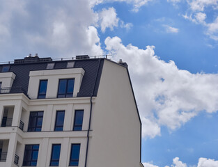 Part of city real estate property and condo architecture. Part of the modern facade of the house. Background of blue sky and white clouds. Fragment of new luxury house.
