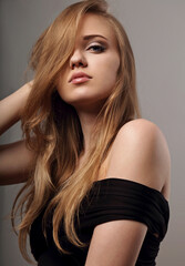 Fototapeta premium Beautiful natural makeup woman with long blond hair style in black dress, pink lipstick looking on grey background.. Closeup glamor