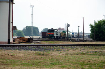 Fototapeta na wymiar An old diesel passenger follows the rails against the backdrop of a morning summer steppe landscape.