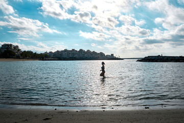 Fototapeta na wymiar Young girl taking a morning bath on a beach of the Mediterranean Sea