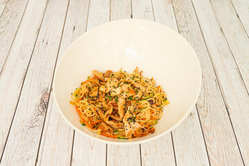 noodles with chicken, vegetables and seeds sauteed with yakisoba sauce in a white bowl