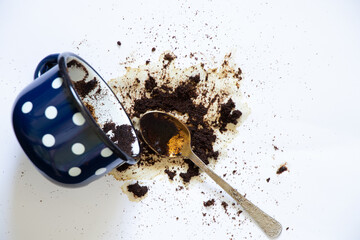 a cup with overturned coffee on a white background and a teaspoon lies next to it, spilled coffee...