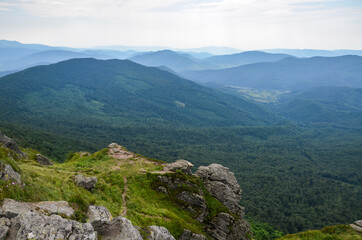 Mountain peak with boulders and forested hills on background at summer day. Pikuj mount, Carpathian mountains, Ukraine