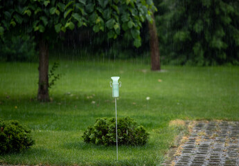 Plastic rain gauge in garden on rainstorm