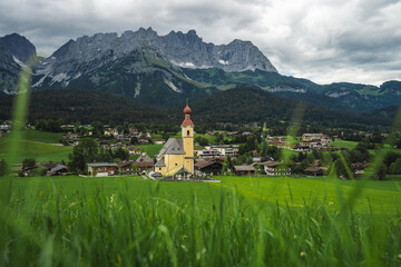 Fototapeta premium Yellow local church in Ellmau. Village of Going. Wilden Kaiser mountains in background. Tirol, Alps, Austria