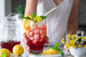 Woman extending hand with a colourful red cold summer drink