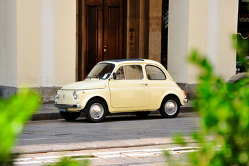 Yellow retro mini car parked on a city street.