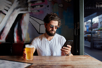 Hipster man enjoying drinking a beer at pub