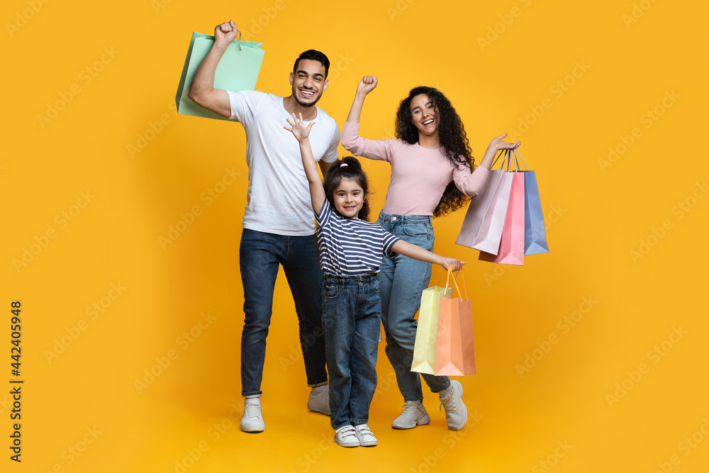 Wall mural Seasonal Sales. Portrait Of Excited Arab Family Of Three Carrying Shopping Bags