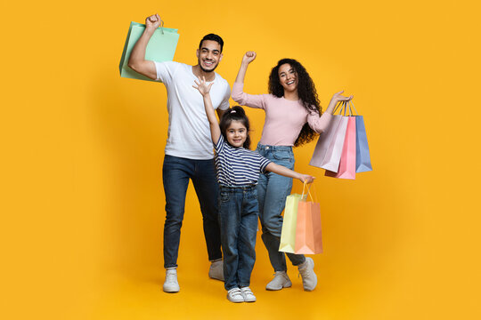 Seasonal Sales. Portrait Of Excited Arab Family Of Three Carrying Shopping Bags