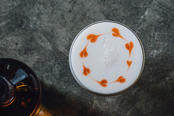Whiskey Sour with foam froth with heart designs on concrete background