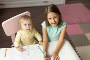 two children draws at the table in the room,