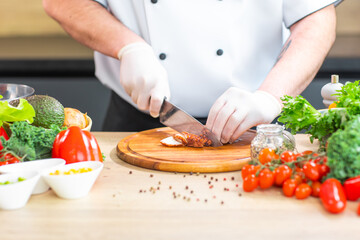 Young chef is cutting octopus in a modern kitchen. The man prepares food at home. Cooking healthy and tasty food.