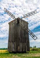 Old abandoned wooden mill and wheat summer field	