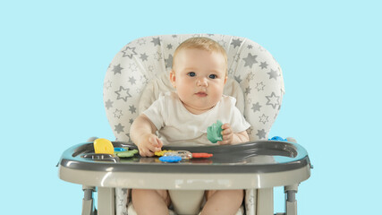 Baby in the feeding chair front view. A six-month-old baby is sitting on a high chair playing with...
