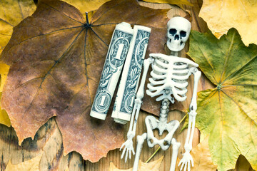 a toy skeleton of a man next to him dollars twisted into a tube