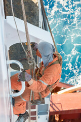 Seaman ship crew working aloft at height painting ships superstructure.