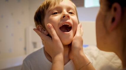 Little boy showing soring throat to his mother. Concept of children illness, disease and parent care