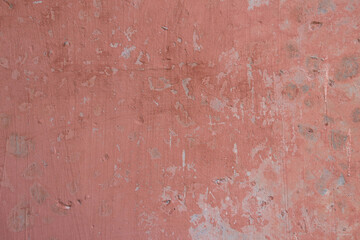 Light red pink concrete wall with cracked peeling paint texture