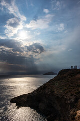 Fototapeta na wymiar Sunset over the Temple of Poseidon at Cape Sounion, Greece. Cliff with dramatic view on mediterranean sea and ruins of an ancient Greek temple with Doric-style columns. Vertical