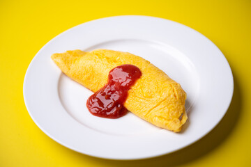 plain omelette with tomato ketchup on yellow background