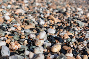 Aegean sea pebble marble stone beach close-up texture. Various rocky surface in sunny Greece near Athens