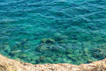 Wild rocky shore close-up on mediterranean sea with clear turquoise water. Travel Greece near Athens. Summer nature wilderness background