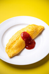 plain omelette with tomato ketchup on yellow background
