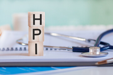 wooden block form the word hpi with stethoscope on the doctor's desktop, medical concept