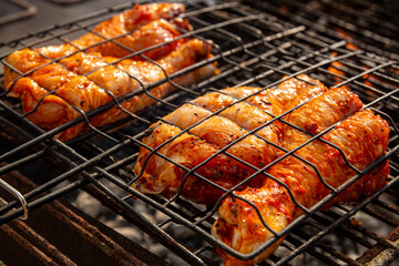 Traditional baked barbecue chicken on a charcoal grill. Grilling and smoking chicken outdoors in nature.