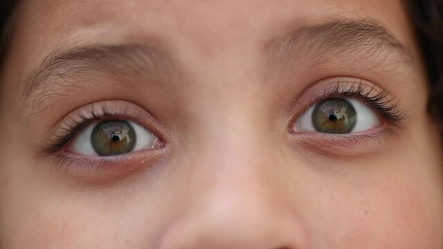 Child eyes wide open with green eye staring camera macro close-up