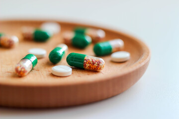 Intestinal-soluble capsules and pills with vitamins on a wooden plate. Close up, macro photo