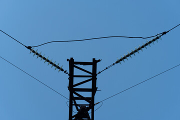 A rusted steel transmission tower in Ukraine supports high-voltage power lines, featuring insulators against a clear blue sky. This image illustrates the aging yet essential infrastructure of the Ukra