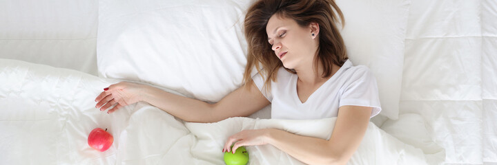 Young woman sleeping in bed with apples in her hands top view