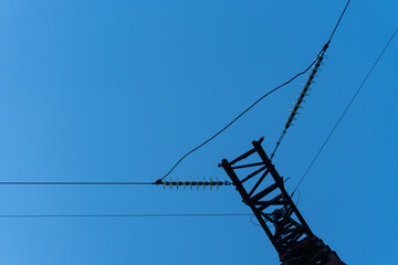 A rusted steel transmission tower in Ukraine supports high-voltage power lines and insulators...