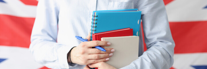 Woman holding books and pen against background of flag of united kingdom
