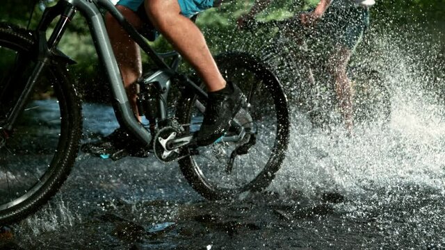 Super slow motion of mountain biker passing a river. Speed ramp effect. Filmed on high speed cinema camera, 1000 fps.